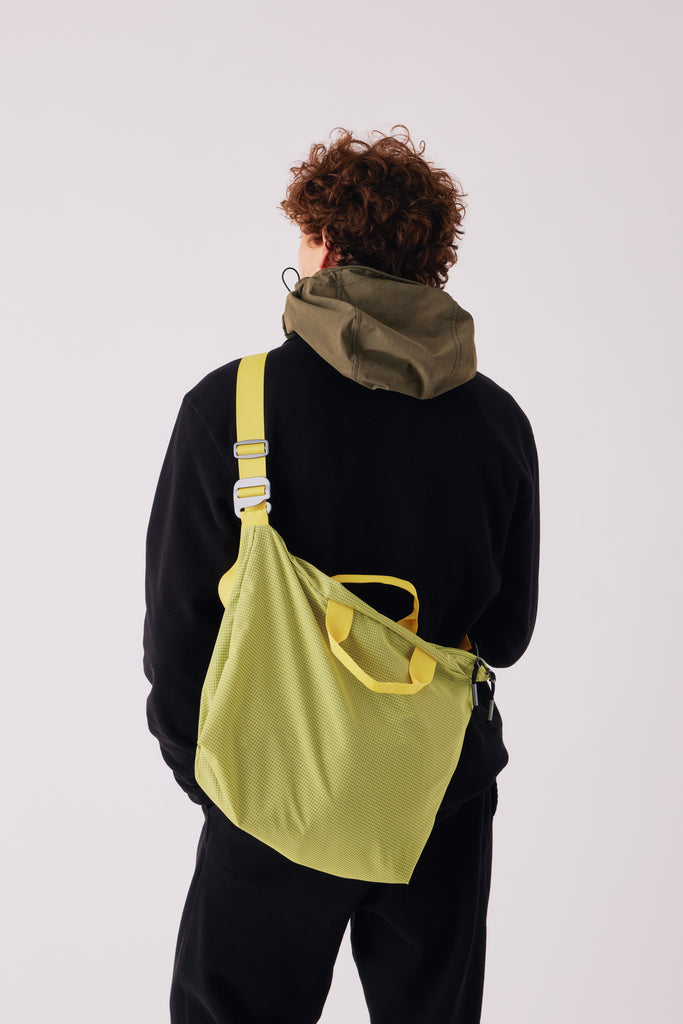 FW26 on-model fit reference. Shown: Raglan Merino Sweater - Black; Zip Tote - Yellow. Photograph 25343.